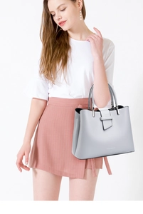 Detail of light grey leather handbag with metal buckle and dual interior compartments