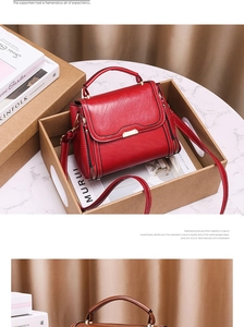 Détail du sac à bandoulière rouge et marron avec fermoir en métal dans un coffret cadeau