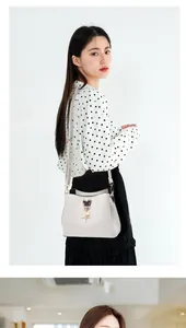 Detailed side view of cream white crossbody bag featuring a chic black heart metal clasp