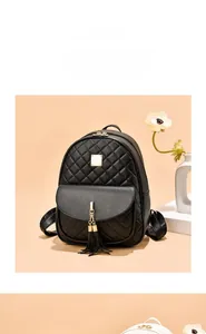 Détail d'un mini sac à dos matelassé noir avec pompon doré et finitions métalliques élégantes