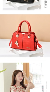 Detail of red crocodile texture handbag with gold hardware and pearl leaf tassel charm