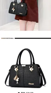 Detail of black crocodile texture handbag with golden hardware and flower pendant charm