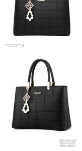 Detailed view of black quilted leather handbag featuring a gold logo and pearl pendant