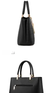 Detail of black quilted leather handbag with gold zipper and pearl charm accessory
