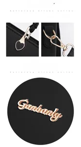 Dettaglio degli accessori a cuore dorati e targhetta logo lucida su borsa in pelle nera