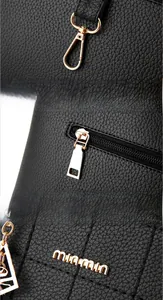 Detail of black litchi leather texture with golden D-ring and brand logo hardware