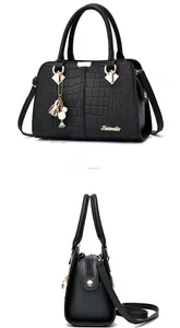 Detail of black faux crocodile leather handbag with metal logo and artistic charm