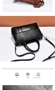 Detail of black faux crocodile skin handbag showing textured leather and dual top handles