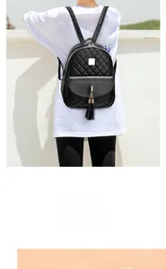 Détail d'un sac à dos matelassé noir avec motif en losange, métal doré et pompon chic