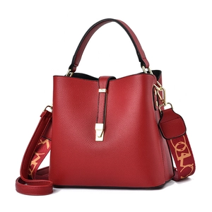Red pebbled leather bucket bag with gold clasp and decorative wide shoulder strap