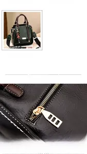 Detail of army green lychee leather bag with brown handles and gold hollow zipper pull