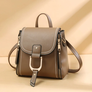 Detailed view of brown leather backpack with gold buckle and white contrast stitching