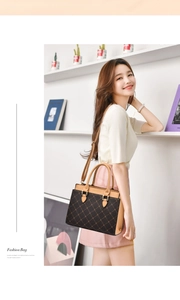 Detail of elegant monogram patterned handbag with brown leather straps and gold hardware