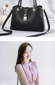 Detail of black lychee grain leather handbag with gold metal buckles and crossbody strap