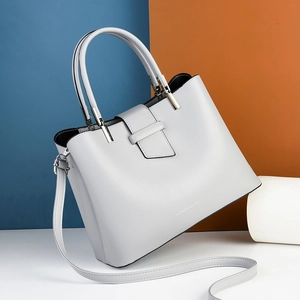 Minimalist light grey leather handbag with top handle and detachable shoulder strap
