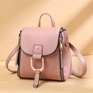 Detail of pink faux leather backpack featuring golden horseshoe buckle and white stitching
