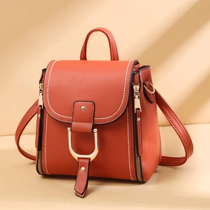 Detail of reddish-brown faux leather bag showing contrast stitching and gold metal buckles