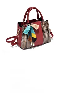 Close-up of red leather handbag featuring houndstooth panels and silk scarf detail