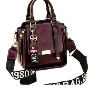 Retro burgundy handbag with wide lettered strap and bear charm on white background