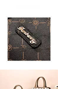 Detailed view of polished metal logo plate and vintage floral pattern on leather handbag