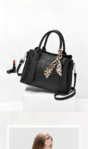 Close-up of black crocodile pattern handbag with leopard print silk scarf and shoulder strap