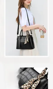 Detail of black crocodile texture handbag featuring a decorative leopard print scarf handle