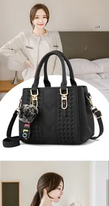 Detail of black pebbled leather handbag with gold hardware and plush pompom charm