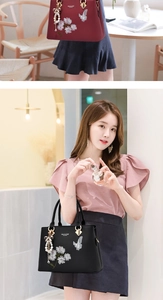Detailed view of floral embroidery and bow pendant on red and black tote bags