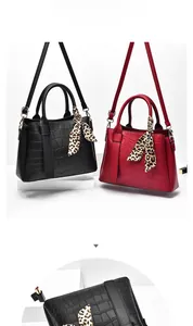 Detail of stone textured handbags in black and red with leopard print silk scarves