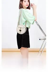 Detail of white round quilted bag with gold chain strap and cat-shaped charm