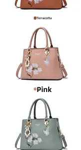 Close-up of elegant floral embroidery and pearl bow charm on a leather handbag