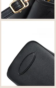 Close-up of litchi grain black leather bag with reinforced bottom stitching and gold buckle