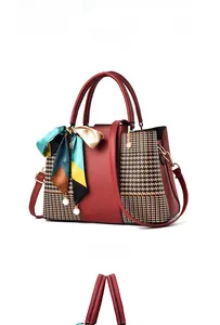Detail of dark red handbag featuring houndstooth pattern panels and decorative silk scarf