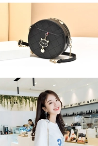 Macro detail of black quilted round bag with cat charm and gold chain strap