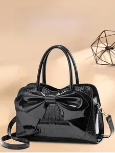 Detail of black patent leather bag with large bow and crocodile embossed texture