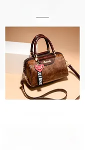Detailed close-up of dark brown crocodile texture boston bag with golden hardware and charm