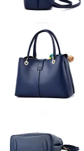 Detail view of navy blue pebbled leather handbag with gold rings and decorative silk scarf