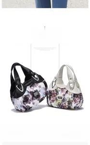 Detail of floral print handbags with leather handles and metal logo on white background