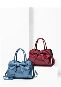 Detail of elegant crocodile-patterned patent leather handbags with large 3D bow decoration
