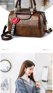 Detail of vintage brown crocodile embossed boston bag with heart charm and webbing strap