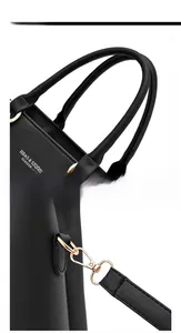 Close-up of black leather handbag featuring round handles and golden metal lobster clasps