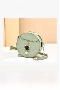 Detail showing mint green quilted round crossbody bag with double straps and cat charm