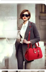 Detail of red leather bag with textured litchi grain and metallic tassel charms