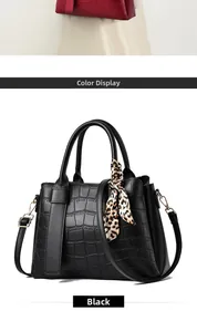 Detail of black faux crocodile leather handbag featuring leopard print silk scarf on handle