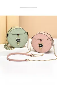 Detail of quilted leather round bags in mint green and pink with cat-shaped metal pendant