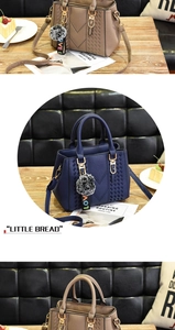 Detail of lychee pattern leather tote bag with woven trim and grey pom-pom charm