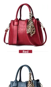 Detail of red crocodile pattern handbag with leopard print scarf and golden hardware