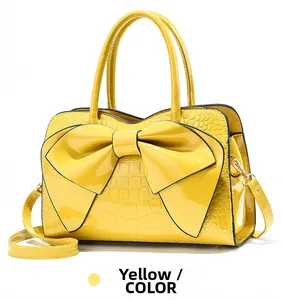 Detail of cream yellow patent leather handbag with large bow and crocodile pattern