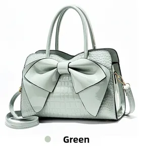 Detail of green patent leather handbag featuring crocodile pattern and large bow