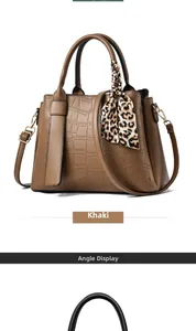 Detail view of khaki faux crocodile handbag featuring leopard scarf and shoulder strap